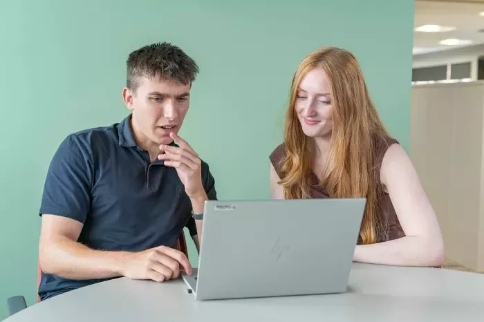 Two people working together on a laptop
