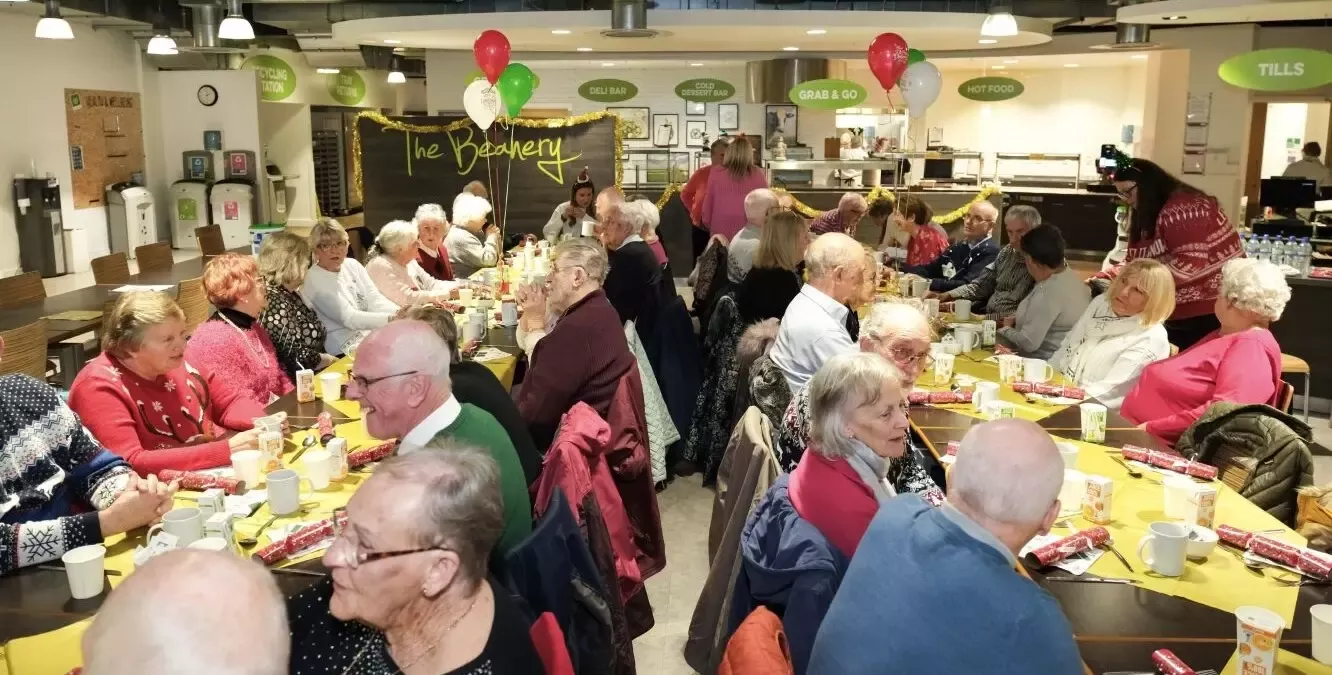 A Christmas decorated canteen filled with around 60 people having a Christmas lunch.