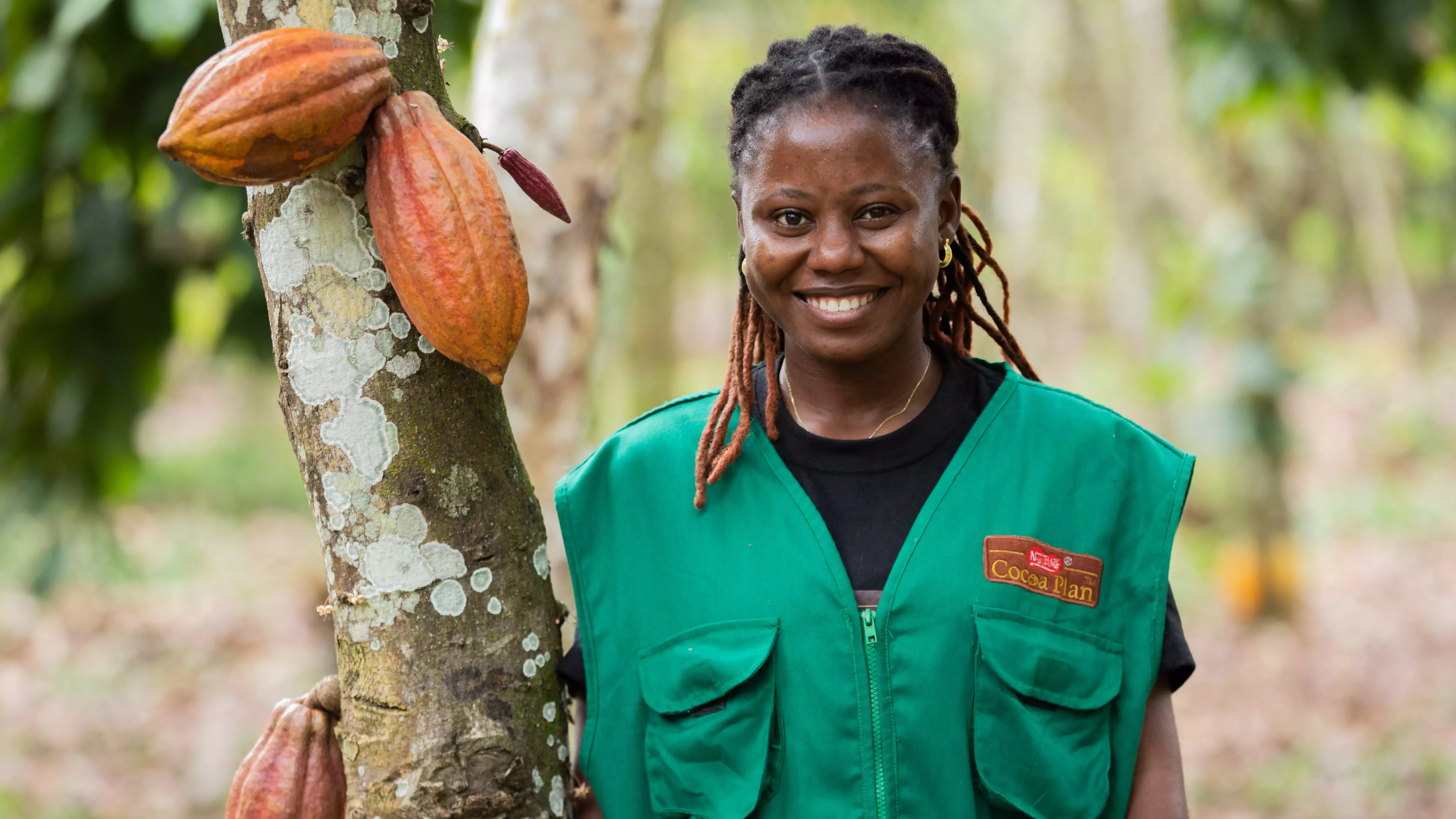 A woman standing next to a cocoa tree.