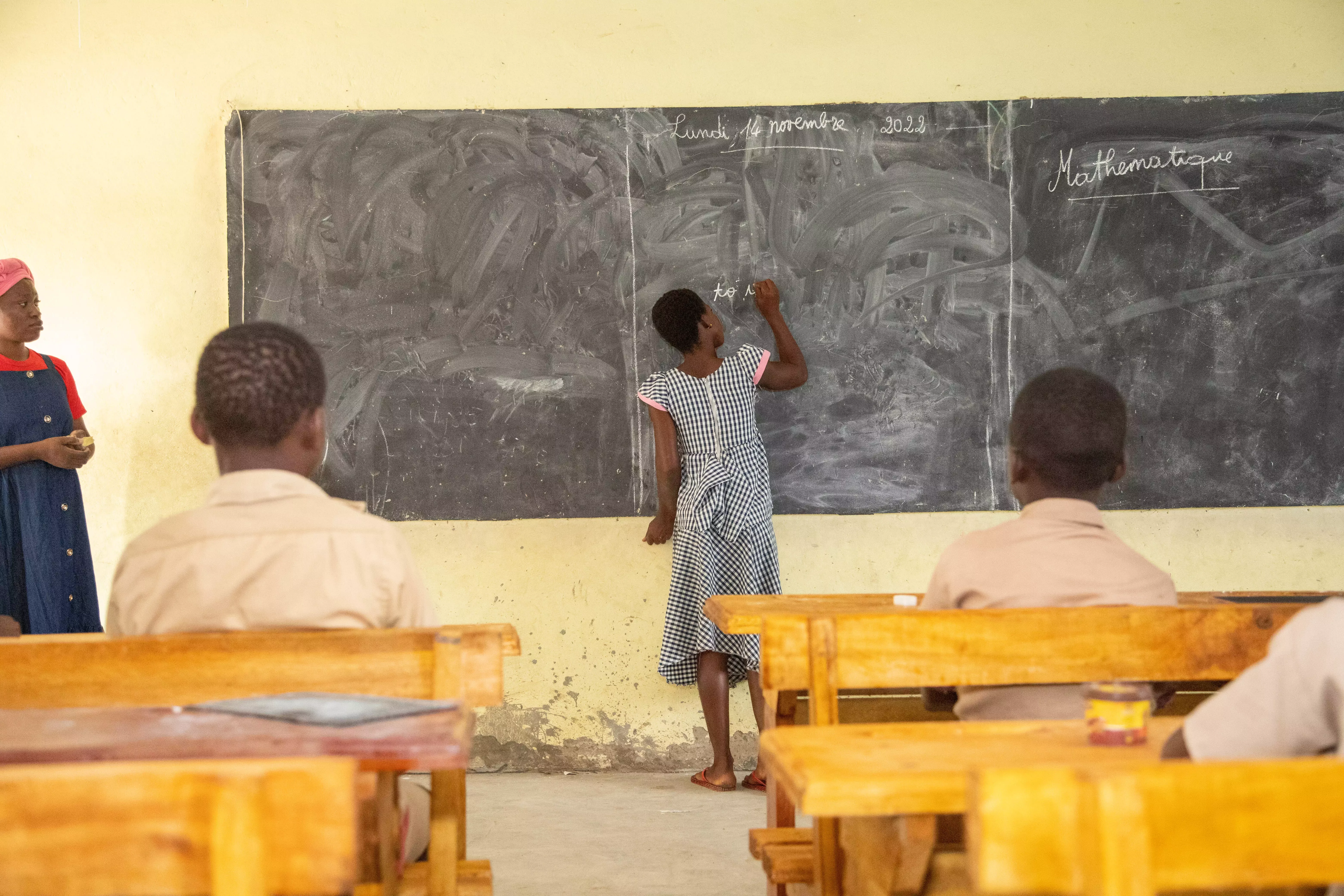 student writing on a chalkboard at school
