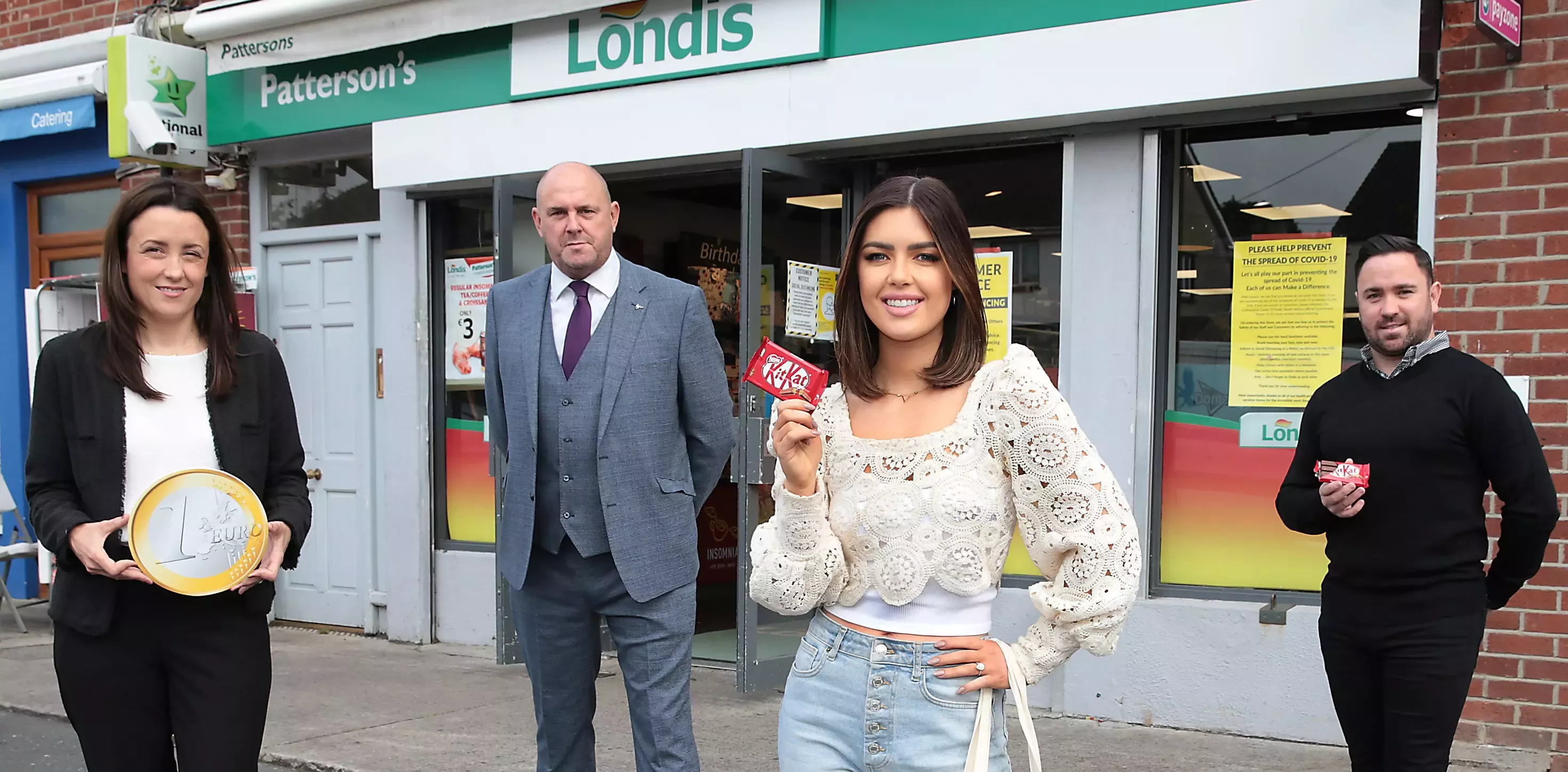 four people stood in front of a londis holding kitkats and a big euro
