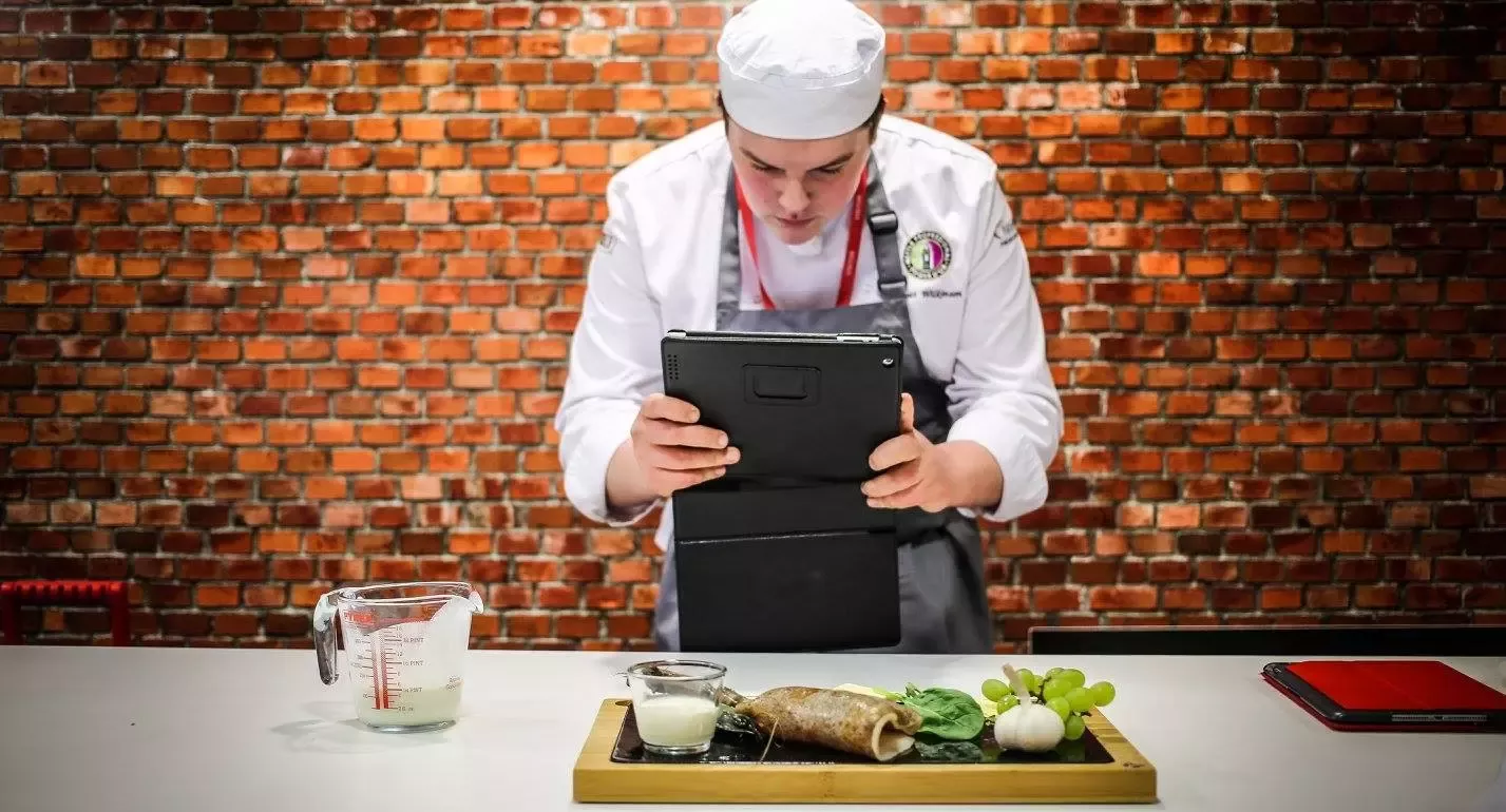 Chef taking a photo of a tray of food
